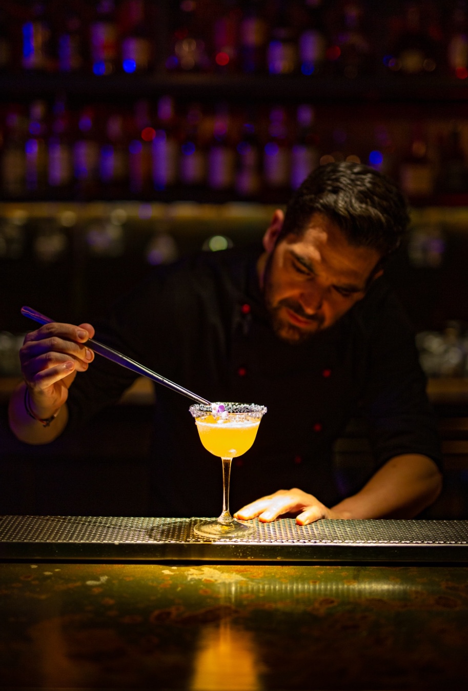 Panagiotis Papavramopoulos finishing a garnish with tweezers at the bar pass